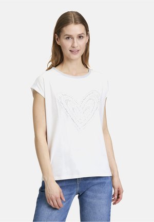T-shirt bianco in cotone a maniche corte, con un motivo decorativo a forma di cuore composto da piccoli accenti metallici e un colletto a costine grigio.