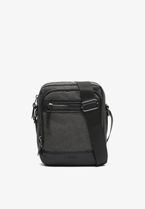 Kompaktne tumedat halli värvi kandekott musta reguleeritava rihmaga, esiküljel lukuga tasku ja nahast põhjakinnitusega.