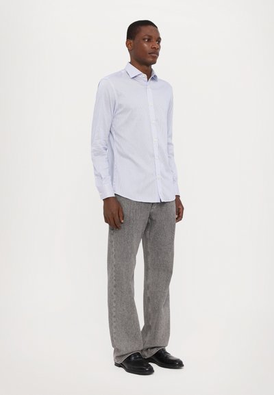Camicia a righe blu chiaro a maniche lunghe, con bottoni e colletto, abbinata a pantaloni grigi con texture e scarpe nere. Look semplice e vestibilità su misura.