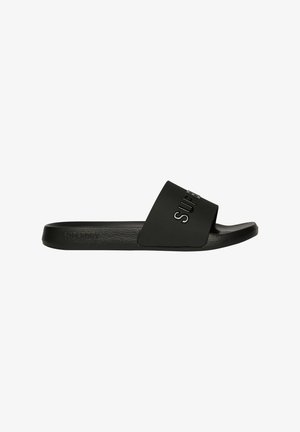 Sort slidesandal med flad sål, der har en bred strop med præget tekst. Fremstillet af glat gummilignende materiale.