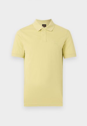Polo à manches courtes de couleur jaune pâle avec deux boutons et un petit logo sur la poitrine sur un fond blanc uni.