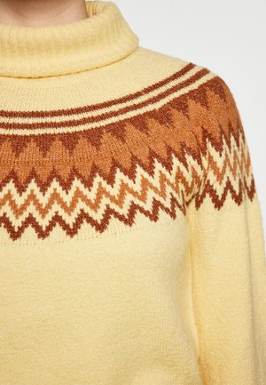 Sweter z golfem wykonany z dzianiny w jasnym żółtym kolorze z brązowym i kremowym wzorem w zygzaki na klatce piersiowej; miękka struktura; ściągacz w kołnierzu.