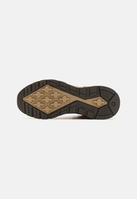 Suela de goma en negro y beige con un patrón texturizado. Presenta diseños hexagonales y en cruz para tracción y durabilidad.