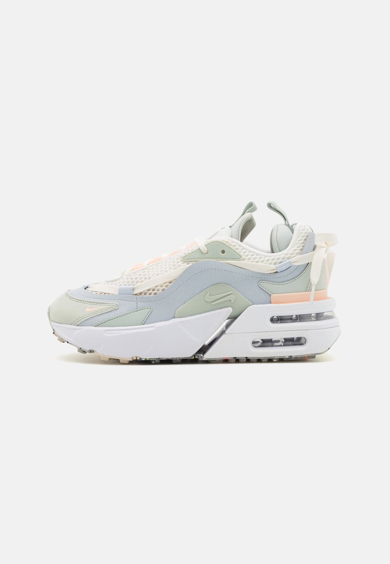 Zapatillas deportivas con un diseño por capas en verde claro, blanco y rosa pálido. Materiales de malla y ante con una suela gruesa y amortiguación de aire visible.