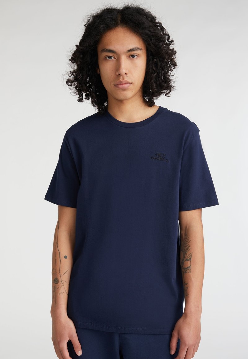 Camiseta de algodón azul marino con mangas cortas, escote redondo, que presenta un sutil logo negro en el pecho y una textura suave.