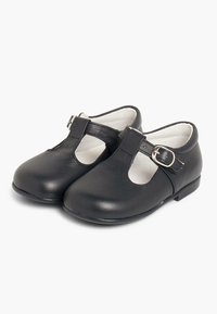 Mustad nahast Mary Jane kingad, ringtoe, T-riba disain, väike kinnitussüsteem ja lamedad kontsad. Sile tekstuur ja minimalistlik disain.
