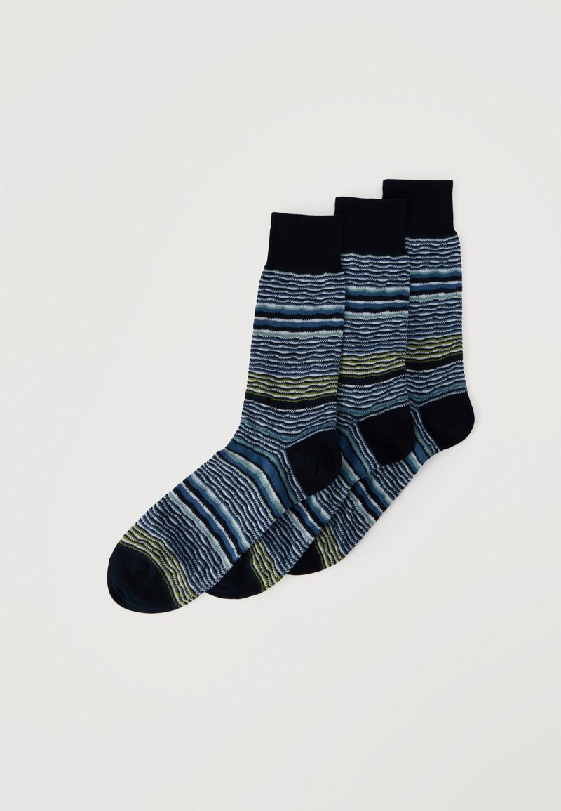 Trois paires de chaussettes à revers noir avec des rayures ondulées horizontales bleues, vertes et blanches, disposées en chevauchement sur un fond blanc.