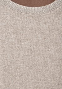 Tessuto beige strutturato con righe verticali; presenta un colletto rotondo con un bordo a coste di colore chiaro. Materiale a maglia morbido.