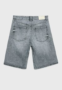 Shorts en denim gris avec une coupe décontractée, cinq passants de ceinture et deux poches arrière avec des accents cousus. Texture usée avec un dégradé inégal.