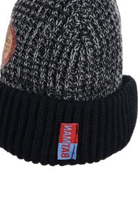 Gorro de punto negro y gris con un puño acanalado, que presenta un parche bordado circular y una etiqueta colorida en el lateral.