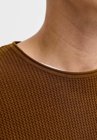 Brauner gestrickter Pullover mit strukturiertem Muster, der einen runden Ausschnitt und gerippte Abschlüsse aufweist, vor einem neutralen Hintergrund präsentiert.