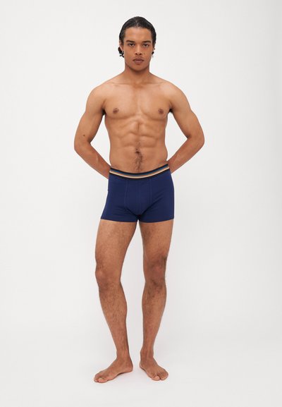 Marineblaue Boxershorts mit einem mehrfarbigen gestreiften elastischen Bund. Hergestellt aus glattem Stoff, enganliegendes Design, mittellange Oberschenkellänge.