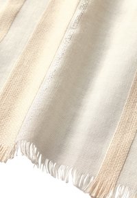 Vævet stof i creame og beige med lodrette striber, der har frynser langs kanterne og en blød tekstur. Afsluttet med subtile glans detaljer.