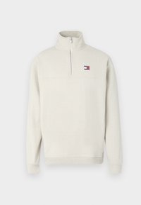 Jasnobeżowa bluza z półzamkiem wykonana z miękkiego materiału. Posiada prążkowany kołnierz i mankiety oraz małą naszywkę z logo na piersi.
