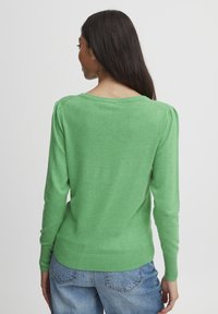 Grüner Strickpullover mit langen Ärmeln, rundem Halsausschnitt und puffierten Schulterdetails. Glatte Textur, gerippte Bündchen und Saum.