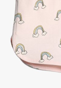 Różowa bawełniana tkanina ma wzór małych, wielokolorowych tęczy z chmurkami, co tworzy radosny design. Miękka faktura i gładkie wykończenie.