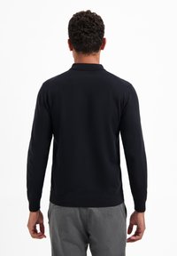 Donkerblauwe pullovertrui met een geribde zoom en manchetten, lange mouwen en een klassieke kraag. Eenvoudige, gladde textuur zonder zichtbare patronen.