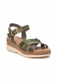 Sandalia de cuña verde de cuero con diseño perforado, correa de tobillo ajustable y suela de goma color crema. Plantilla de aspecto de madera.