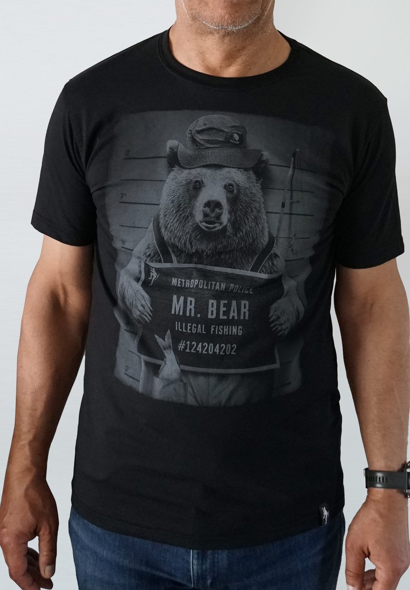Black cotton t-shirt featuring a bear in police attire, holding a sign that says "MR. BEAR, ILLEGAL FISHING," with a mugshot backdrop.