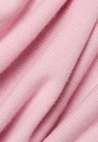 Heller rosa gestrickter Stoff mit einer weichen, strukturierten Oberfläche, der eine Nahaufnahme zeigt, die das gerippte Muster und die dezente Flauschigkeit hervorhebt.