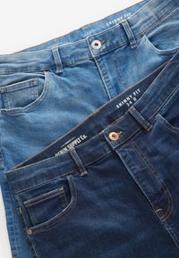 Dva para skinny fit kavbojk, ene svetlo modre in ene temno modre, z petimi žepi, podrobnostmi iz bakrene barve in šivi.