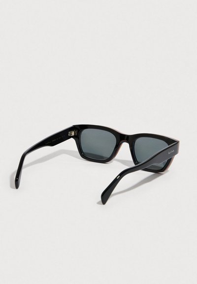 Gafas de sol rectangulares negras con lentes grises. Montura de plástico lisa con acabado brillante y sutiles detalles en rojo en los bordes.