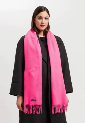 Sciarpa di lana rosa con estremità frangiate, appoggiata intorno al collo, indossata sopra un cappotto nero. Presenta un'etichetta con il logo in basso. Tessuto liscio.