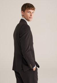 Črni krojeni blazer z enim razporkom, zapenjalnimi manšetami in odprtim ovratnikom. Gladko blago z modernim in prilegajočim se dizajnom.