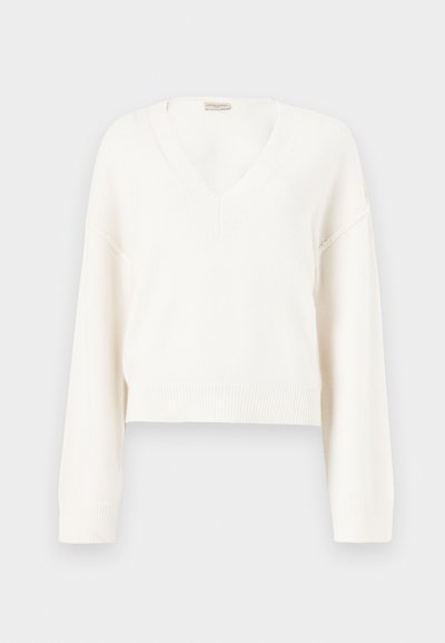 Pull court en tricot blanc avec manches longues et col en V, présenté sur un fond neutre.