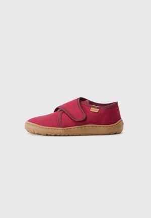 Zapatos de tela rojos con una correa de velcro, punta redondeada y suela de goma beige. Textura suave con costuras mínimas y un pequeño logo en el lateral.
