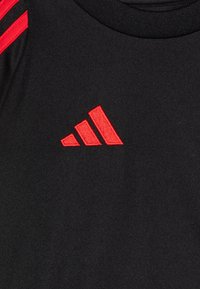 Černé sportovní tričko s červeným designem tří pruhů na ramenou a červeně vyšitým logem. Hladká textura s kulatým výstřihem.