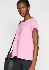 Ροζ κοντομάνικο τοπ από απαλό ύφασμα, με στρογγυλή λαιμόκοψη και άνετη εφαρμογή. Φορεμένο με μαύρο κολάν και μαύρη τσάντα.