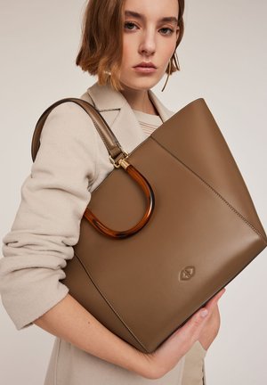 Braune Leder-Shopper-Tasche mit glänzender Oberfläche, ausgestattet mit einem großen braunen Acrylgriff und einem dezenten, geprägten Logo an der Unterseite.