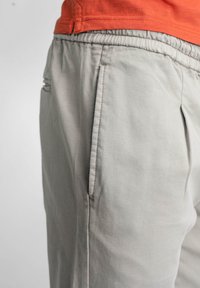 Lichtgrijze katoenbroek met een soepele textuur, elastische tailleband en zijzakken. Inclusief plooien voor een relaxte pasvorm.