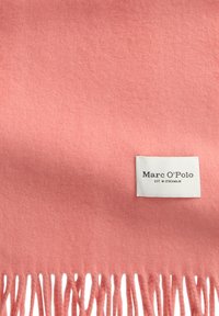 Écharpe en laine rose pâle avec des bords frangés et une étiquette de marque blanche portant l'inscription "Marc O’Polo, Est. à Stockholm."