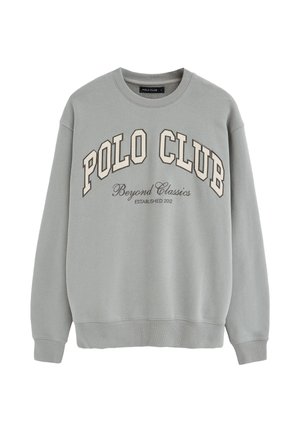 Jasnoszara bluza z okrągłym dekoltem, z dużym napisem "POLO CLUB" oraz mniejszym napisem "Beyond Classics Established 2012" poniżej.