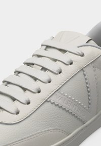 Άσπρο sneaker από δερμα με υφή, με άσπρες κορδόνια και ανάγλυφο λογότυπο "VALENTINO" στη πλευρά, με κυματιστές λεπτομέρειες στο τελείωμα.