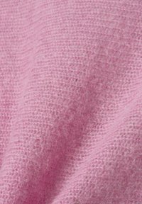Nahaufnahme eines weichen, flauschigen, rosa gestrickten Stoffes mit einer leicht erhöhten Gewebestruktur und sichtbaren Fasern im natürlichen Licht.