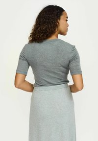 Top gri cu mânecă scurtă dintr-un material moale, cu un decolteu rotund clasic și o siluetă ajustată, asociat cu o fustă gri asortată.