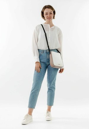 White crossbody bag with beige accents, smooth texture, adjustable strap, rectangular shape, and subtle brand logo on the front.