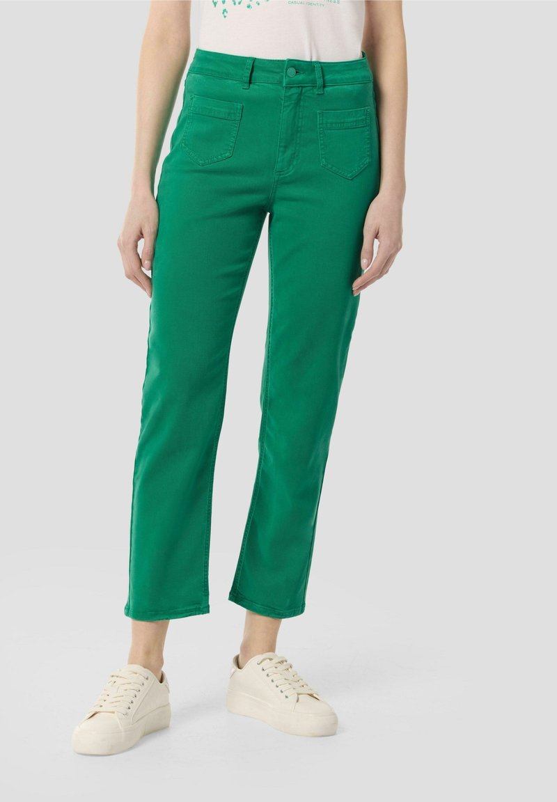 Grüne Baumwollhosen mit hoher Taille, geradem Bein und fünf Taschen. Getragen mit beigen Sneakers, was einen lässigen Fit und eine strukturierte Silhouette zeigt.