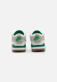 White and green Nike sneakers with a smooth upper, contrasting rubber sole, logo accents, and padded green inside collar.
