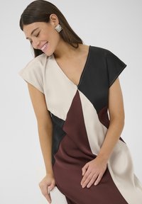 Rochie cu blocuri de culoare, prezentând panouri bej, negru și burgundy, realizată dintr-o țesătură fină, cu decolteu adânc în V și mâneci scurte.