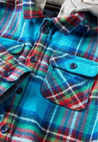 Karierte Hemd in Blau-, Rot-, Grün- und Weißtönen. Aus Flanell mit einer weichen Textur gefertigt. Verfügt über zwei Brusttaschen und dunkle Knöpfe.