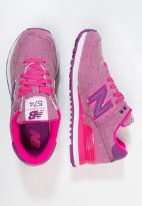 Ett par rosa och lila New Balance 574-sneakers, med vy ovanifrån och sidoprofil, med ljusrosa snören och vita mellansulor.