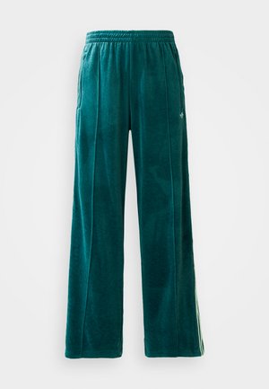 Teal velour joggers with a loose fit, elastic waistband, side pockets, and subtle texture pattern. Features contrasting stripes along the sides.