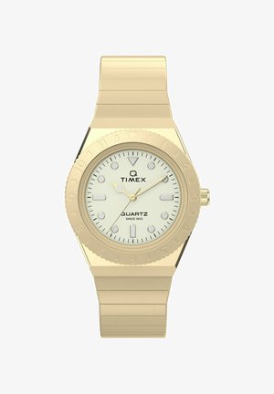 Zlatisté hodinky Timex Q so bielym ciferníkom, luminiscenčnými markerami a kovovým remienkom, zobrazujúce čas 10:11:10.