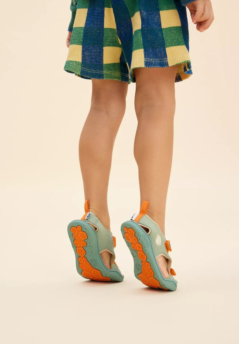 Sandali per bambini con una combinazione di colori verde e arancione, dotati di suola testurizzata e cinghie regolabili. Materiale leggero e design aperto.