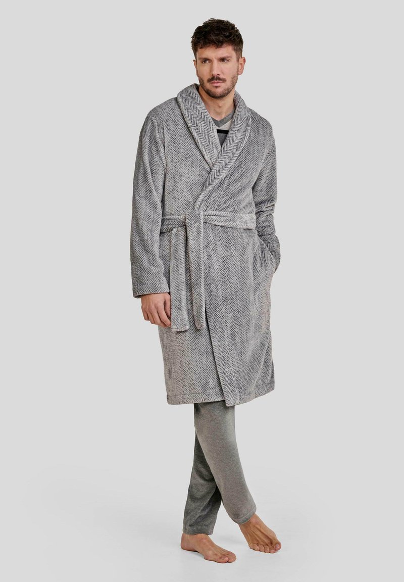 Bata de baño gris en espiga con cuello de chal y cintura ajustable, acompañada de pantalones de chándal gris claro. Tejido suave y corte relajado.