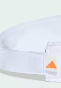 Biała czapka wykonana z gładkiego materiału z usztywnionym daszkiem. Posiada teksturowany pasek z pomarańczowym detalem logo Adidas po boku.